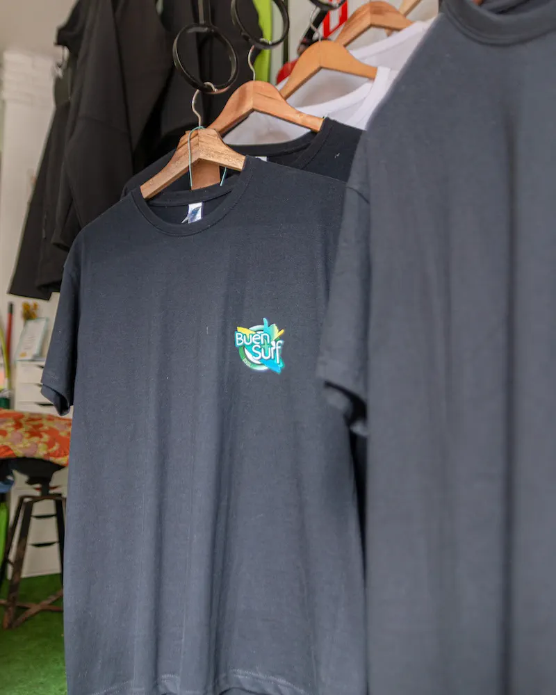 Buen Surf School T-shirts on wooden hangers in the shop