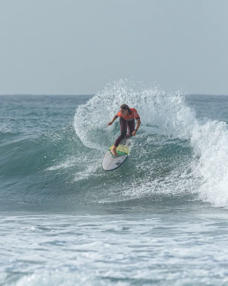 A surfer laying a turn into the foam, the wave breaking behind