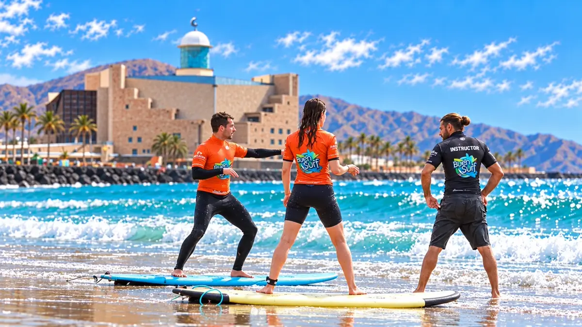 An instructor teaching two students the pop up on the sand at La Cicer, with the Auditorio Alfredo Kraus behind them
